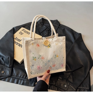 Close-up of white lace tote bag with floral patterns and a large wooden button detail