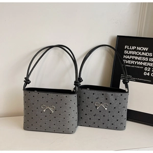Detail of grey polka dot canvas tote with black rope straps and silver bow charm