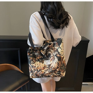 Detailed back view of a floral jacquard tote bag with black canvas straps on a model
