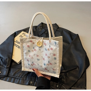 Detail of floral lace fabric handbag with a yellow wooden button and woven handles