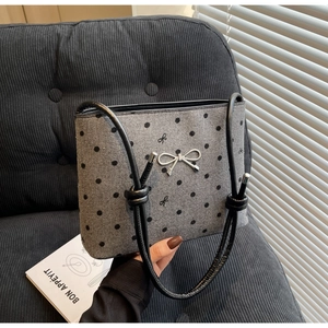Detail of grey canvas polka dot bag with silver bow charm and knotted black leather handle