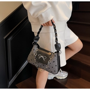 Polka dot handbag detail featuring woven leather handle and silver flower charm chain