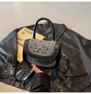 Detail of silver bow metal buckle on a gray heart pattern fabric baguette bag
