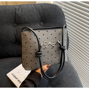 Close-up of gray fabric shoulder bag with heart patterns and silver bow decoration