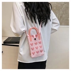 Detailed back view of pink knitted mini mobile bag with heart pattern on a model