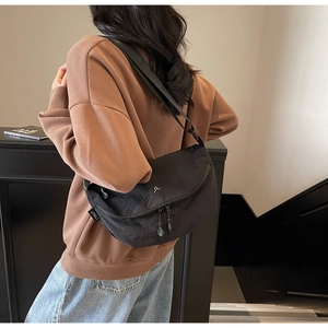 Primo piano della borsa a tracolla in nylon nero con logo JL argento e tracolla larga
