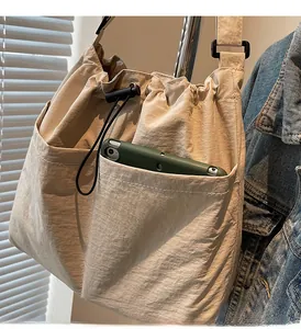 Detail of beige nylon drawstring bucket bag with dual front pockets for storage