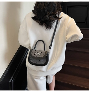 Polka dot tweed baguette bag with silver bow buckle on model on stairs