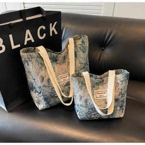 Detail of vintage floral jacquard tote bags in two sizes on a black leather sofa