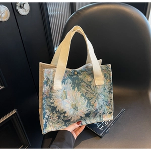 Detailed close-up of Monet floral jacquard fabric and durable webbing handle on a tote bag