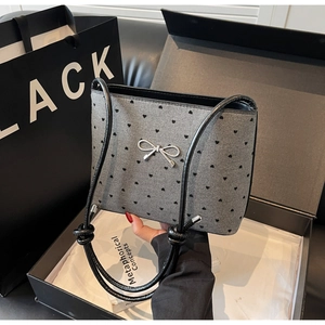 Detailed view of grey shoulder bag with black heart patterns and silver metallic bow