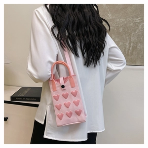 Detail of pink knitted mini bag featuring 3D crochet hearts and woven shoulder strap