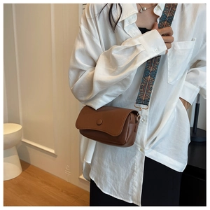 Brown lychee leather crossbody bag with a wide bohemian woven geometric shoulder strap