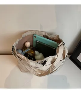 Spacious interior of beige canvas drawstring bucket bag holding a tablet and cosmetics