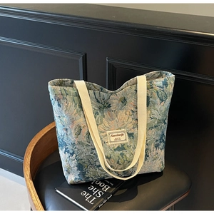 Close-up of floral jacquard tote bag with textured fabric and woven handles on a black chair