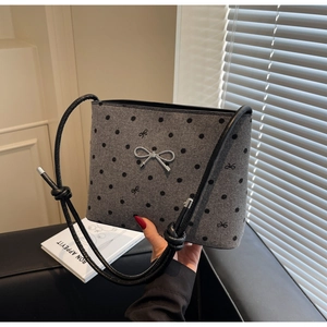 Detail of grey polka dot canvas bag with silver metal bow and embroidered accents