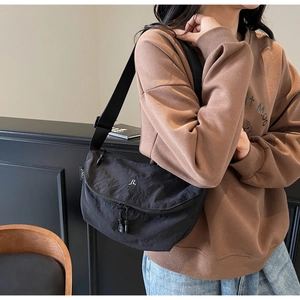 Dettaglio della borsa a tracolla in nylon nero con logo metallico e tracolla regolabile