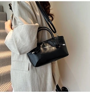 Détail d'un sac cabas en cuir verni noir porté par un mannequin avec logo FASHION BAG blanc