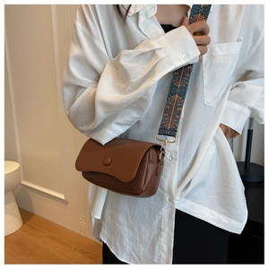 Detail of vintage brown lychee leather crossbody bag with colorful bohemian wide strap