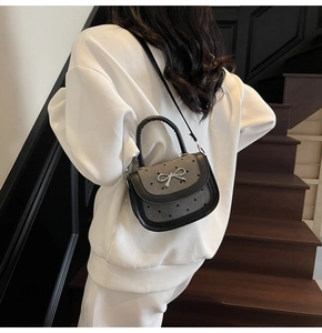 Close-up of a stylish bow knot crossbody bag with grey faux leather trim and silver metal detail