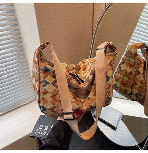 Detailed close-up of colorful geometric woven pattern and wide shoulder strap on hobo bag