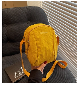 Détail du sac à bandoulière en nylon jaune avec logo de la marque et tissu résistant à l'eau