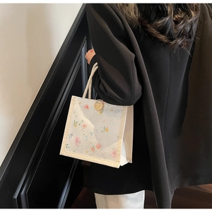 Detail of floral lace tote bag with woven cotton rope handle and wooden button closure