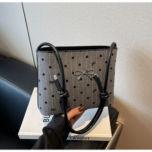 Detail of grey polka dot canvas shoulder bag with silver metal bow and knotted strap