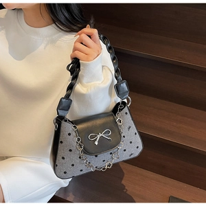 Close-up of grey polka dot handbag with silver bow detail and floral metal chain link