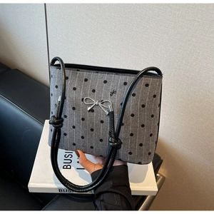 Detailed shot of canvas polka dot bag with silver bow buckle and knotted leather handle