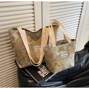 Close-up of two vintage floral jacquard tote bags with cream straps on a leather sofa