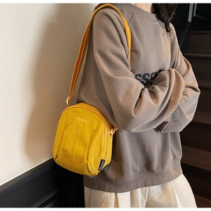 Gros plan sur un sac bandoulière en nylon jaune vif avec bandoulière réglable et logo