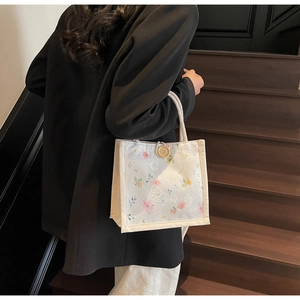 Detailed close-up of a floral lace tote bag featuring wood button and woven rope handle