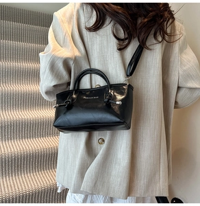 Détail d'un grand sac cabas noir avec lettrage blanc et détails de nœuds décoratifs