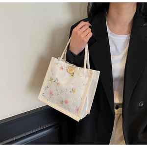 Close-up of beige lace handbag with floral patterns and sturdy white cotton rope handles