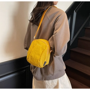 Gros plan sur la sacoche jaune vif en nylon avec bandoulière réglable et broderie