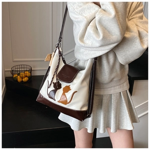 Photo portée du grand sac fourre-tout blanc avec bordure marron et broderie de chat