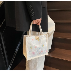 Detail of white floral lace tote bag with woven rope handle and vintage button closure