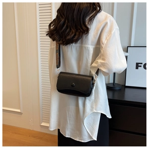 Litchi texture black crossbody bag with colorful embroidered wide strap shown on model