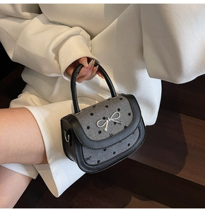 Detailed view of grey wool bag with black bow print and silver metal butterfly lock