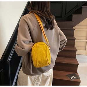 Détail d'un mini sac bandoulière jaune vif en nylon avec broderie et étiquette tissée