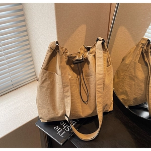 Detail of khaki nylon drawstring bucket bag with side pockets and adjustable strap