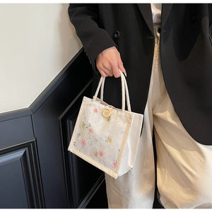 Close-up of beige lace handbag with floral patterns and large wooden button detail
