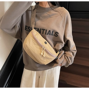 Dettaglio del borsello in nylon beige con cerniere viola e etichetta del brand Jinli