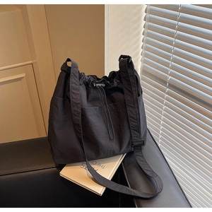 Close-up of black nylon drawstring bucket bag with side pocket and adjustable wide strap