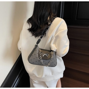 Detail of grey heart-patterned fabric underarm bag with silver bow buckle and floral chain