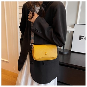 Close-up of bright yellow pebbled leather crossbody bag with vintage patterned wide strap