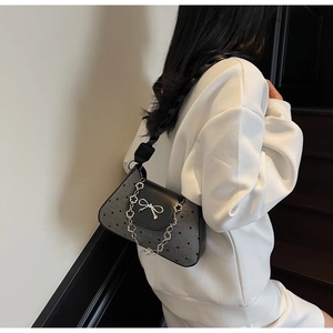 Detail of grey wool shoulder bag with black polka dots and silver bow buckle on flap