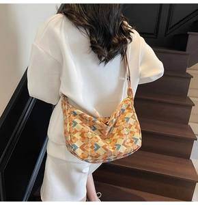 Detail of bohemian tote bag with geometric patterns worn over a white tracksuit