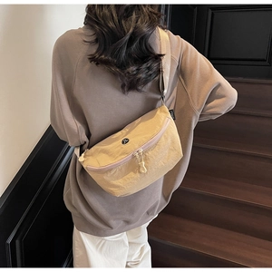 Dettaglio borsa a tracolla in nylon beige con cinturino regolabile e logo del brand